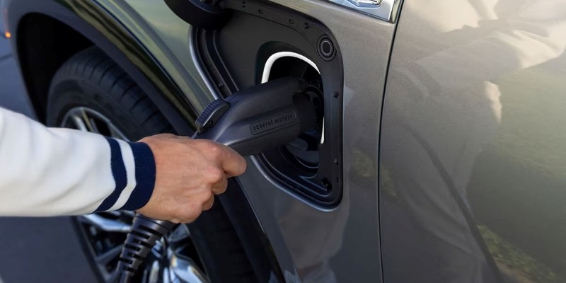 A person plugging a charging cable into the electric vehicle charging port of a car.