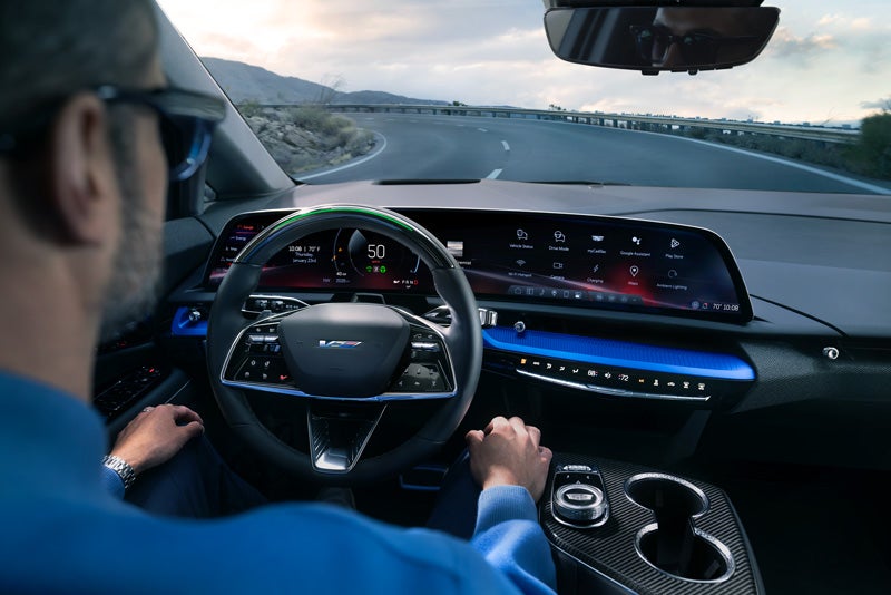 Front View of the 2026 OPTIQ-V Driving Through the Dusk Utilizing its Headlights | Coast Cadillac in Port Richey FL