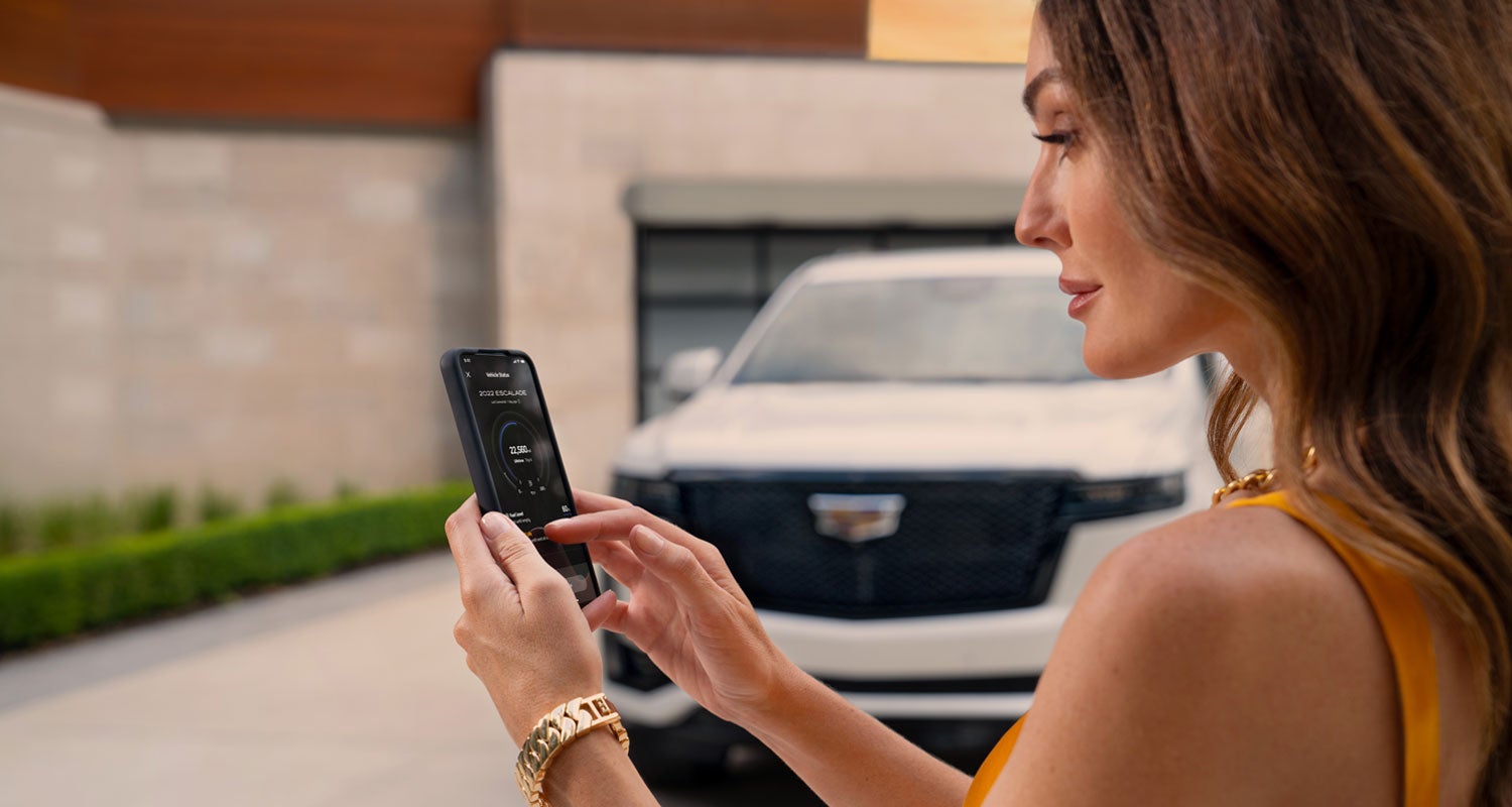 lady checking her mobile with a Cadillac vehicle background | Coast Cadillac in Port Richey FL